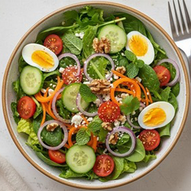 Folhas verdes, pepino, tomates cereja, cenoura ralada, cebola roxa, ovos cozidos e  nozes.